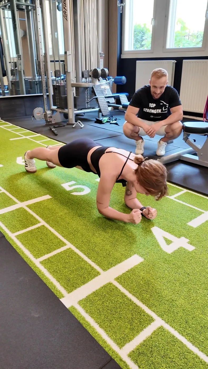 Exercice de gainage sur la piste en gazon synthétique, sous le regard du coach, au studio Top Strength à Lyon 6