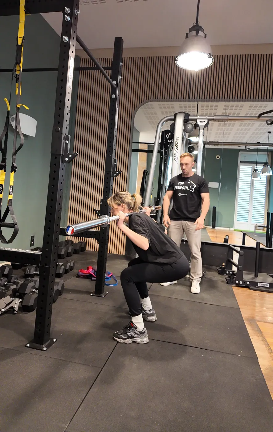 Squat avec barre sous le regard du coach, au studio Top Strength à Lyon 6