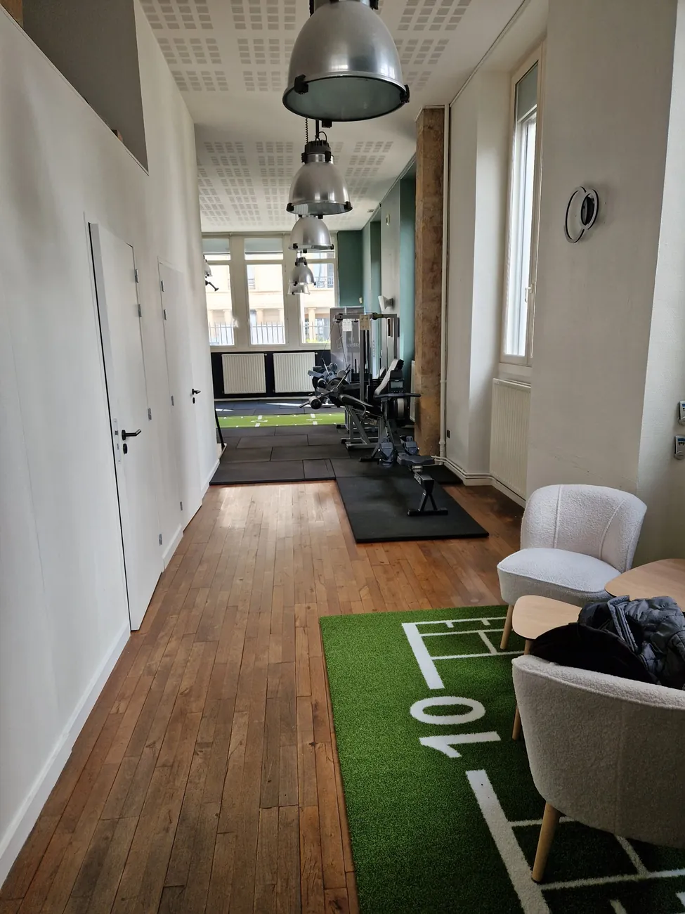 Espace d'accueil du studio Top Strength à Lyon 6 : parquet, fauteuils et vue sur la salle