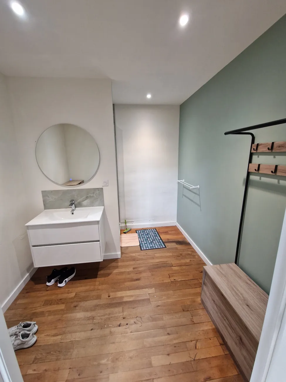 Vestiaire du studio Top Strength à Lyon 6 : vasque, miroir, portants et banc
